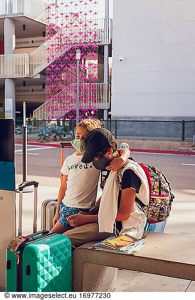 Brothers waiting for airport transportation while using smart phone