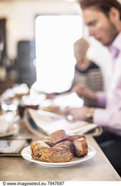Brotstücke auf dem Restauranttisch mit Geschäftsleuten im Hintergrund