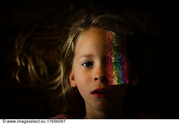 Brown eyed child with rainbow light over her eye