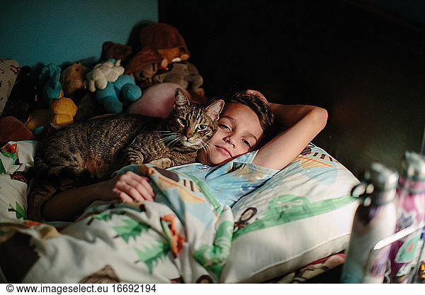 Brown tabby cat snuggles up agains the cheek of his ten year old human