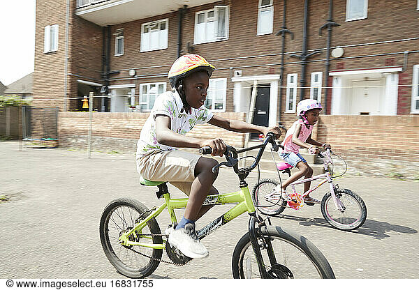 Bruder und Schwester Reiten Fahrräder in sonnigen Nachbarschaft