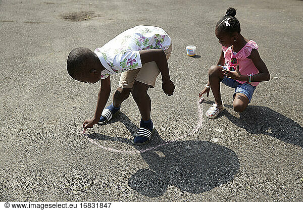 Bruder und Schwester spielen mit Bürgersteig Kreide auf sonnigen Bürgersteig