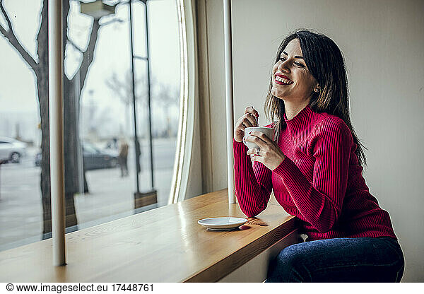 Brunette woman drinking coffee while smiling