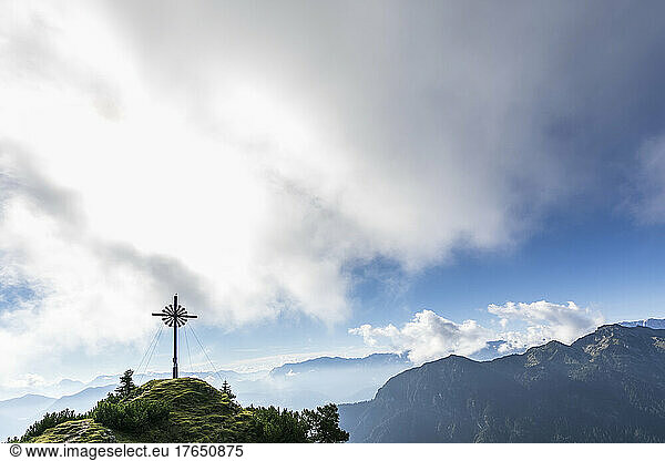 Brunstlkopf summit cross on mountain under cloudy sky