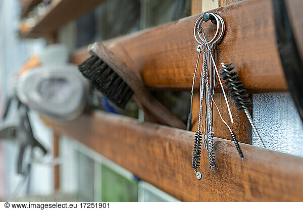 Brush and work tools hanging on wood at workshop