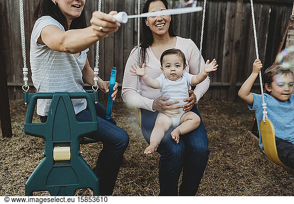 Bubble fun on swings with baby  young boy and two moms