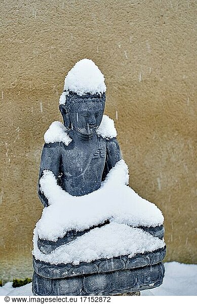 Buddha-Statue aus Stein unter dem Schnee in der Wintersaison in einem Garten.