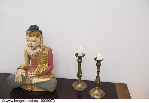 Buddha statue in lotus position with two candles  Munich  Bavaria  Germany