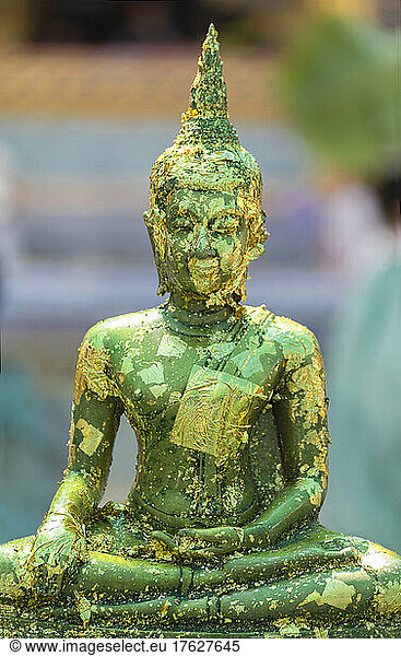 Buddha statue with gold leaf flaking at the Grand Palace Bangkok.