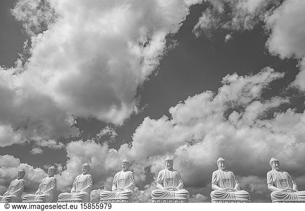 Buddha statues in row under cloudy sky