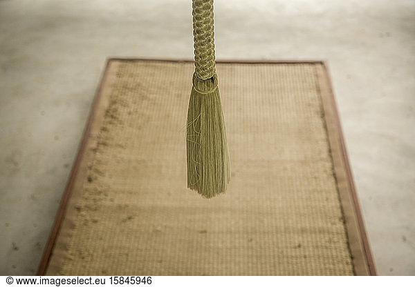 Buddhist bellÂ´s rope and meditation mat on gray floor