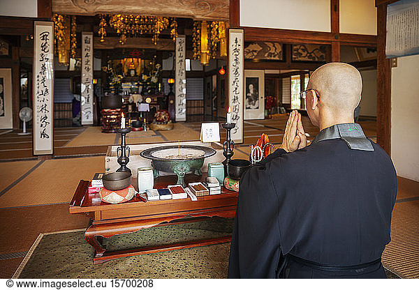 Buddhist priest kneeling in Buddhist temple  praying.