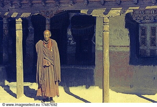 Buddhistischer Mönch vor Kloster in Tikse  1974  Buddhismus  Klosterleben  Glaube  Klostermauern  einzel  alleine  buddhistisches Kloster  Mönchskutte  Mönchskleidung  Ladakh  Himalaya  Indien  Asien