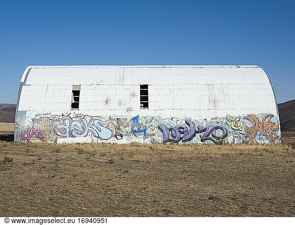 Building in a desert with a domed roof  damage  abandoned  with graffiti tags.