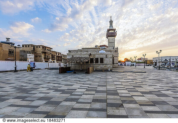 Building in town square under cloudy sky at sunset