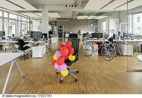 Bunch of balloons on chair in open plan office