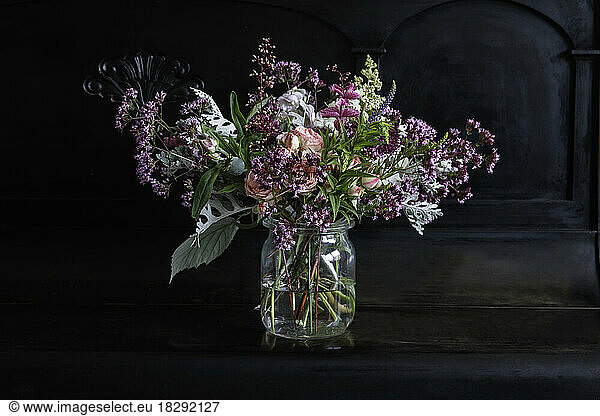 Bunch of flowers in glass jar on black piano