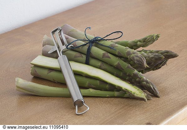 Bunch of green asparagus with peeler on the table