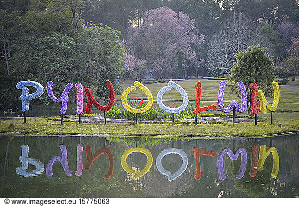 Bunte Buchstaben spiegeln sich in einem See in einem Park in Myanmar.