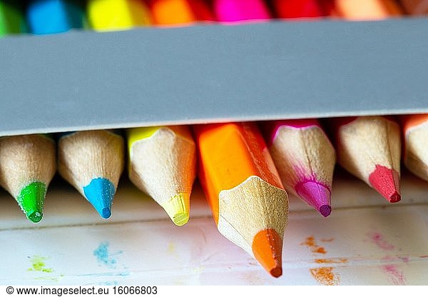 Buntstifte in einem Karton graue Box  Regenbogenfarben  orange Bleistift sticht aus Makro  Schule oder Bürobedarf Hintergrund.