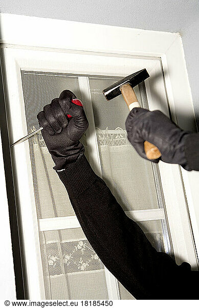 Burglary hand with gloves on window  close-up