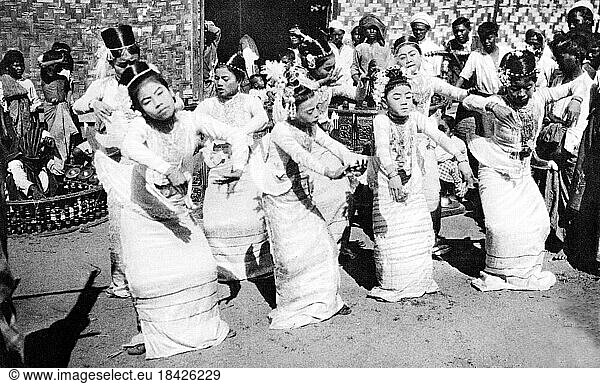 Burma/ Myanmar: A young Burmese ballet troupe performs in the street accompanied by a 'saingwaing' band  c.1920s.A traditional Burmese orchestra  or 'saingwaing'  is composed of wind instruments  Burmese trumpets ('ne')  brass gongs ('mow') and the large barrels or drum circles also known as 'saingwaing' which are lined with hanging tambourines. Troupes are still popular today at Buddhist festivals and national events.