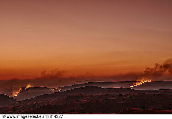 Burning Savannah with orange sky in background at sunset  KwaZulu-Natal  Drakensberg  South Africa