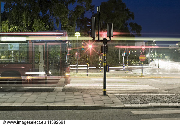 Bus by light trails on street in city at night