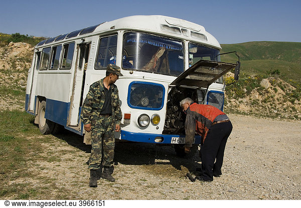 Busfahrer repariert einen Bus auf einer Gebirgsstraße,  Kasachstan