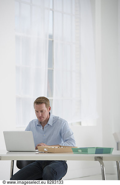 Business. A Man Sitting At A Desk Using A Laptop.
