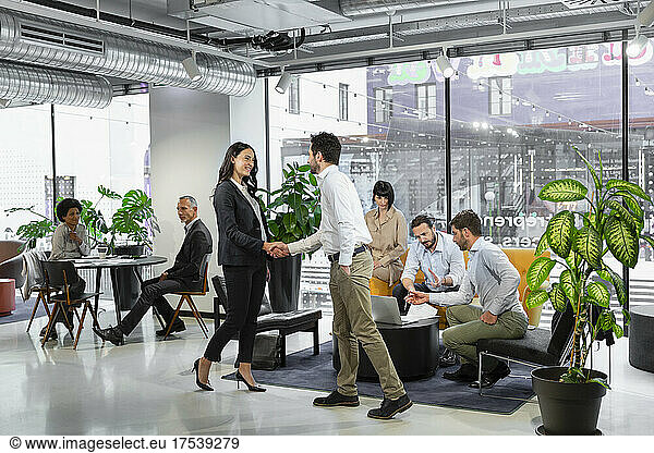 Business colleagues handshaking in office lobby