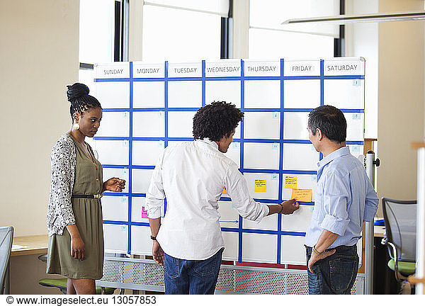 Business colleagues planning strategy on whiteboard in office