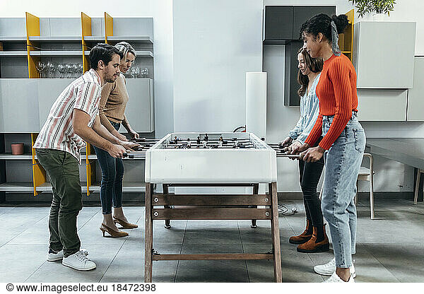 Business colleagues playing foosball together at office