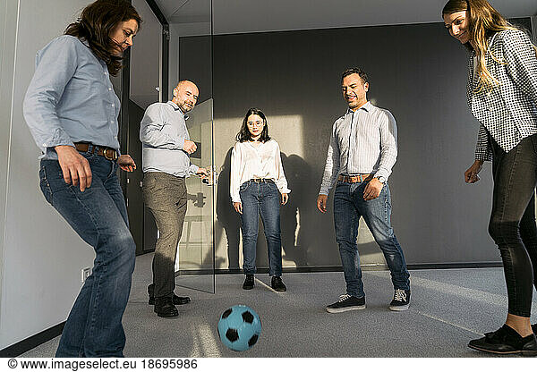 Business colleagues playing soccer in office