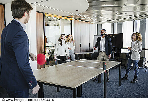 Business colleagues playing table tennis in coworking office