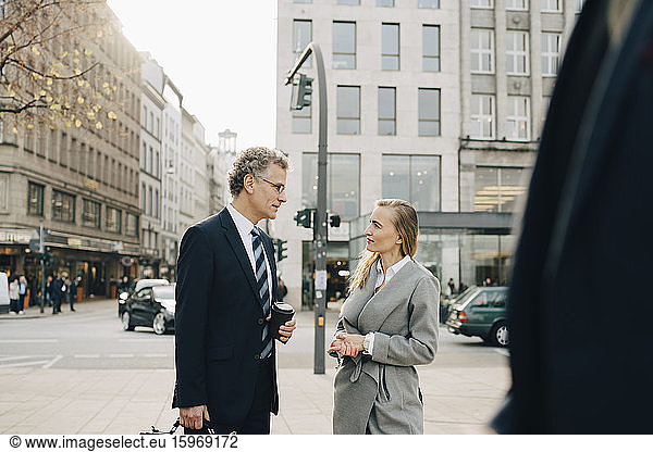 Business colleagues talking while standing in city