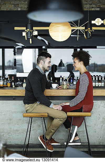 Business couple sitting face to face at cafe counter