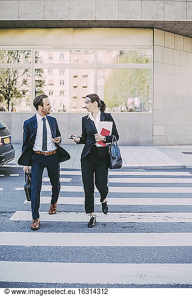 Business coworkers talking wile crossing road in city
