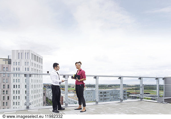 Business man and woman talking on rooftop