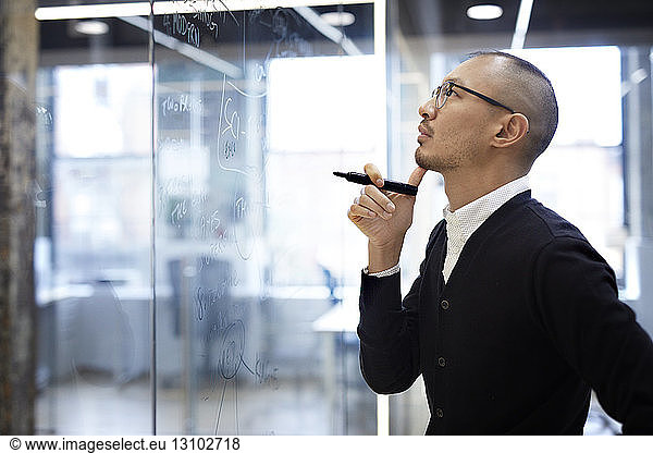 Business man looking at plan on glass wall in office