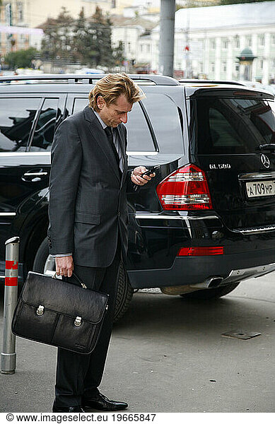Business man standing by a mercedes car  Moscow  Russia.