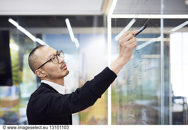 Business man writing on glass in office