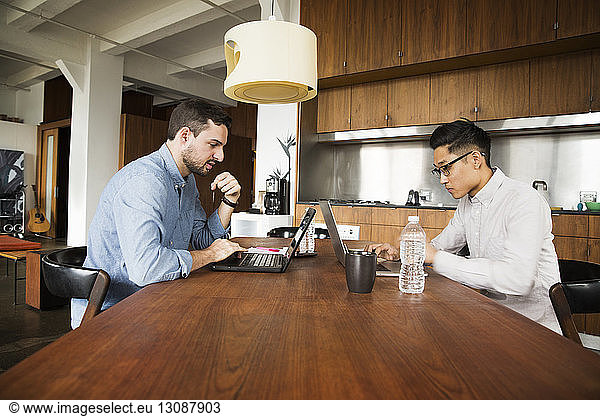 Business partners using laptop computer on table at creative office