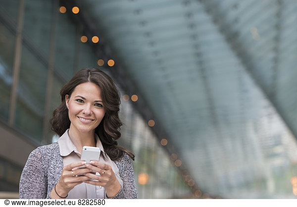 Business People. A Businesswoman In A Light Grey Jacket  Using Her Smart Phone.
