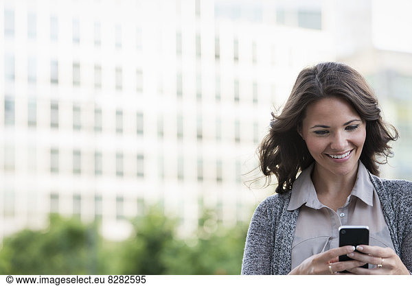 Business People. A Businesswoman In A Light Grey Jacket  Using Her Smart Phone.