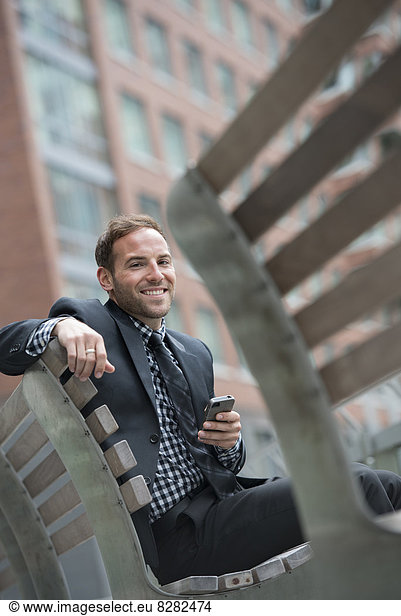 Business People. A Man In A Suit  Sitting On A Bench.