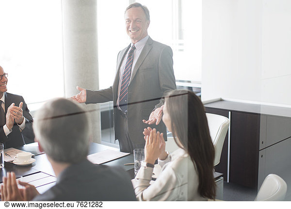 Business people applauding colleague in meeting