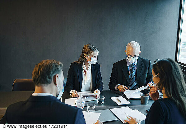 Business people brainstorming over document in board room during pandemic