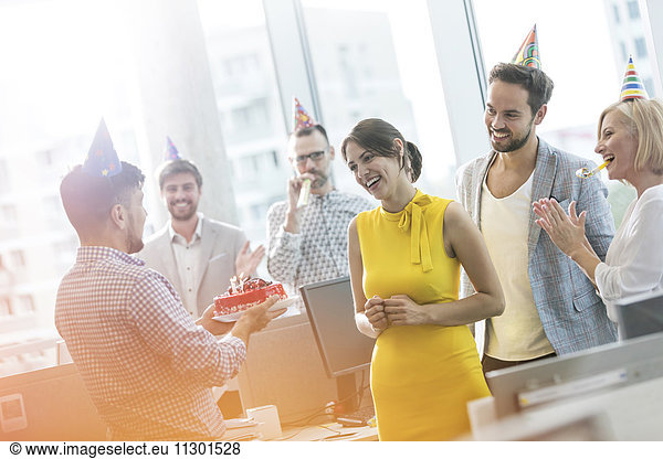 Business people celebrating birthday with cake in office