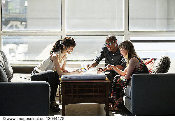 Business people checking blue prints on table in creative office